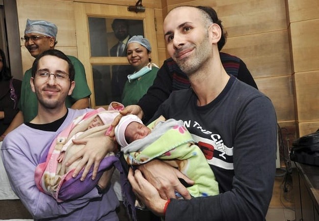 Image: Mauro and his partner Juan Carlos from Spain hold their twin babies at private hospital after an Indian surrogate mother delivered twin baby girls for them in New Delhi