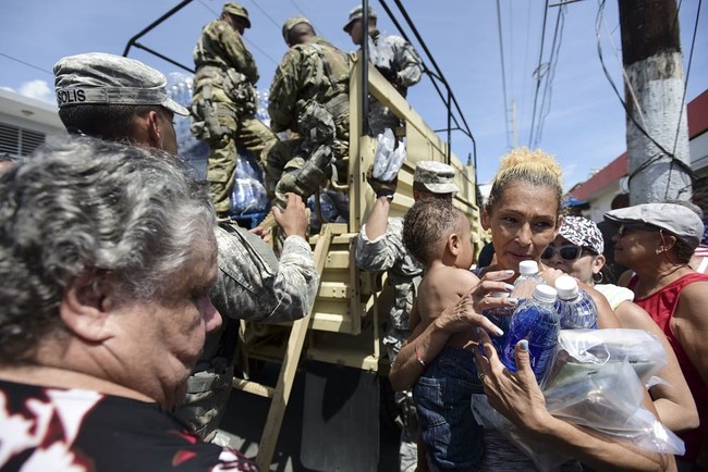 National Guard Soldiers arrive at Barrio Obrero in Santurce to distribute water and food among those affected by the passage of Hurricane Maria, in San Juan, Puerto Rico, Sunday, Sept. 24, 2017. Gov. Ricardo Rossello said "This is a major disaster." "We've had extensive damage. This is going to take some time." (AP Photo/Carlos Giusti)